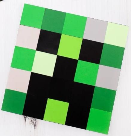 Various shade of green squares, white squares, and black square arranged to make a Minecraft creeper.