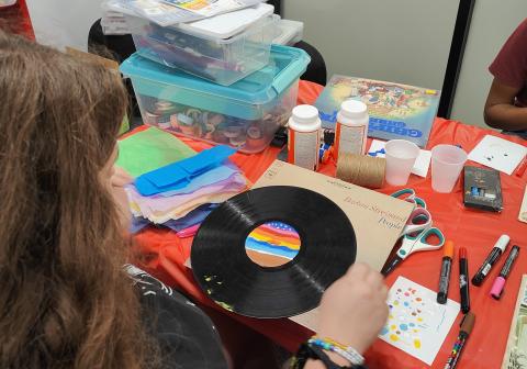 teen girl decorating a vinyl record with paint pens and other art supplies