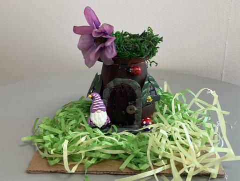 terra cot pot house with door and windows, paper grass, and gnome in purple hat