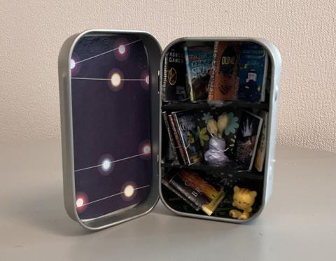 Altoid tin with shelves and mini books, flower vase, and yellow cat