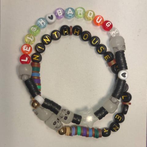 Picture of two beaded bracelets. One with an author's name and the second with the name of two books.