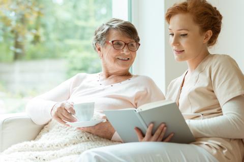 an older and a younger women reading together from a book