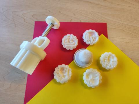 Mooncake mold with a couple molds and clay on red and yellow paper.