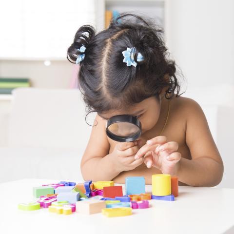 toddler girl looking through magnifying glass
