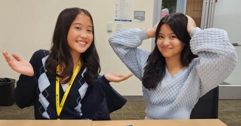 Two girls throwing up their hands in playful confusion.