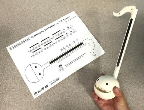 sheet music and hand holding white Otamatone