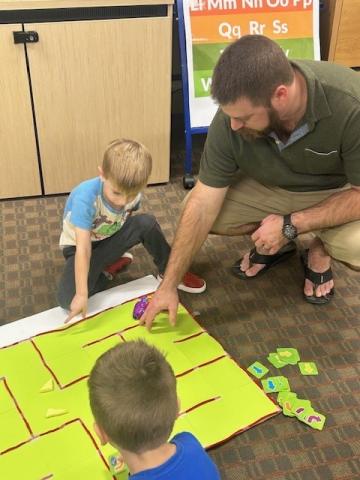 parent helping children move robot mouse in maze