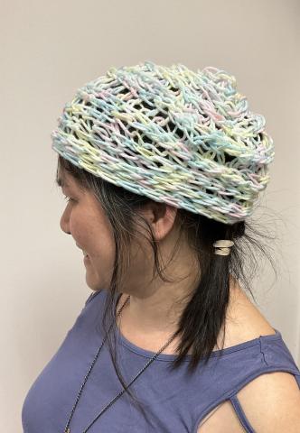 person in a purple top wearing a pastel knitted beanie