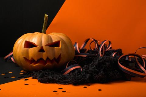 carved pumpkin with black ribbons against orange background