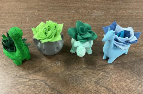 green dinosaur planter, gray cat planter, light green turtle planter, and blue llama planter