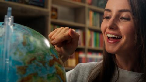 Woman smiling touching a point on a globe