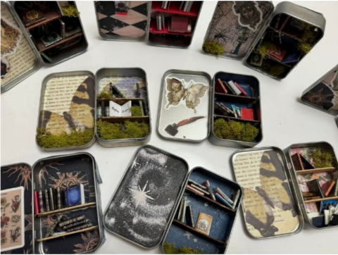 Several Altoid tins decorated with scrapbook paper, tiny books, and dried moss.