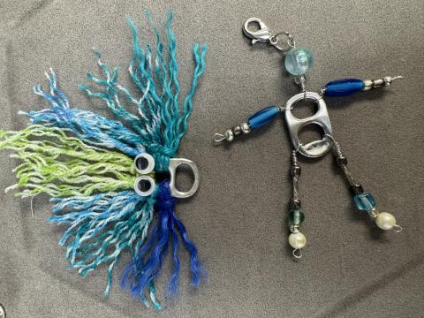 Face with string hair and a person made out of beads and pop tabs