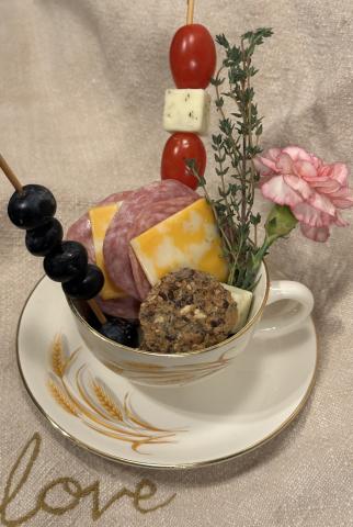 Vintage teacup and saucer, filled with fruit, cheese and salami.