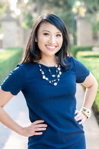 author Tracy Badua stands outside in a blue dress