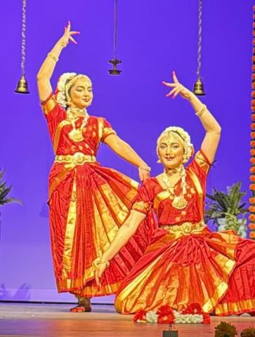 2 teen girls dressed in red and yellow outfits for Indian dance