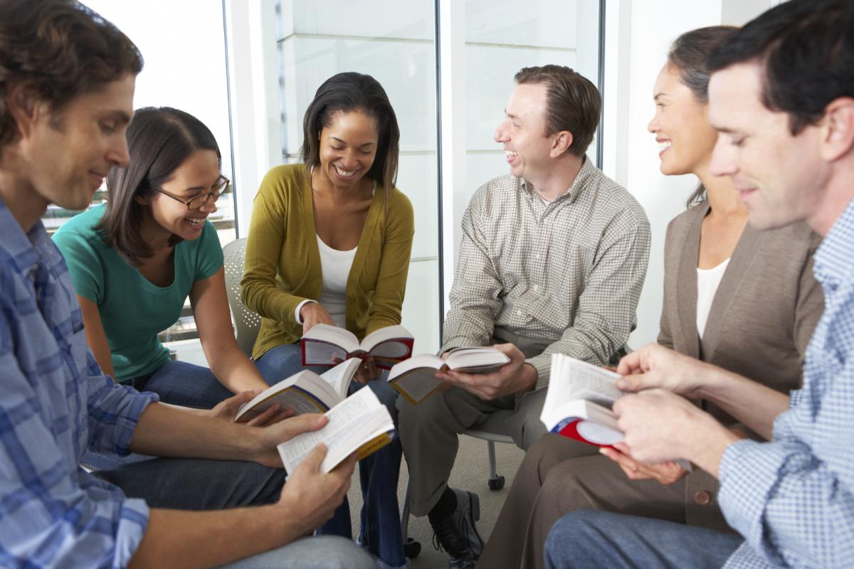 People sitting in a circle holding books and smiling