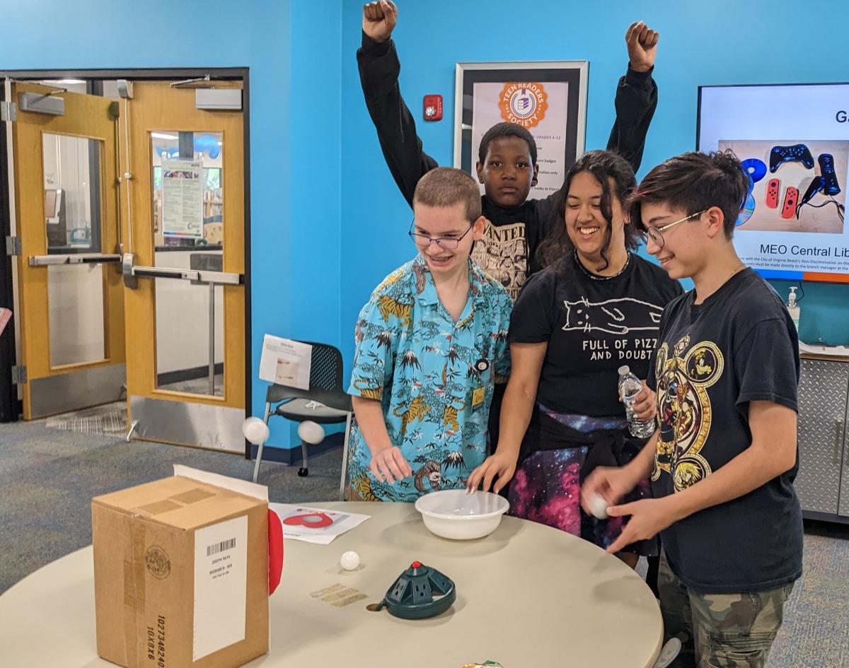 4 teens playing a game with Ping Pong balls