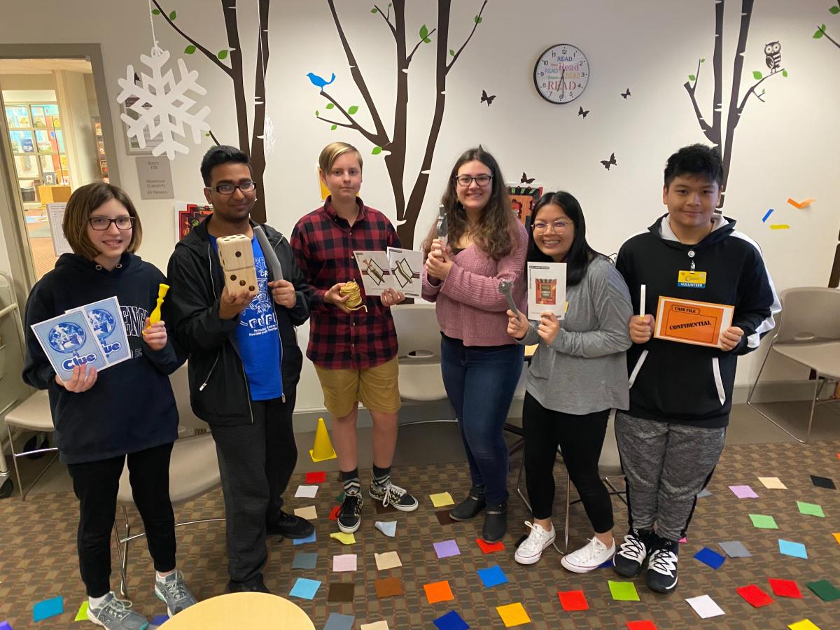 Teens holding overlarge Clue materials.