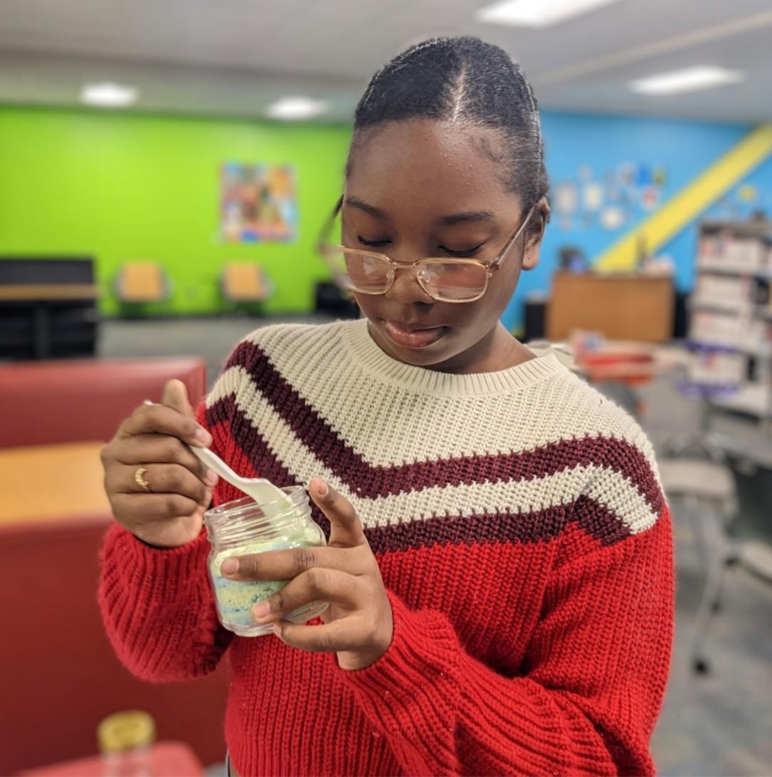 Teen with a glass jar of colored bath fizzies.