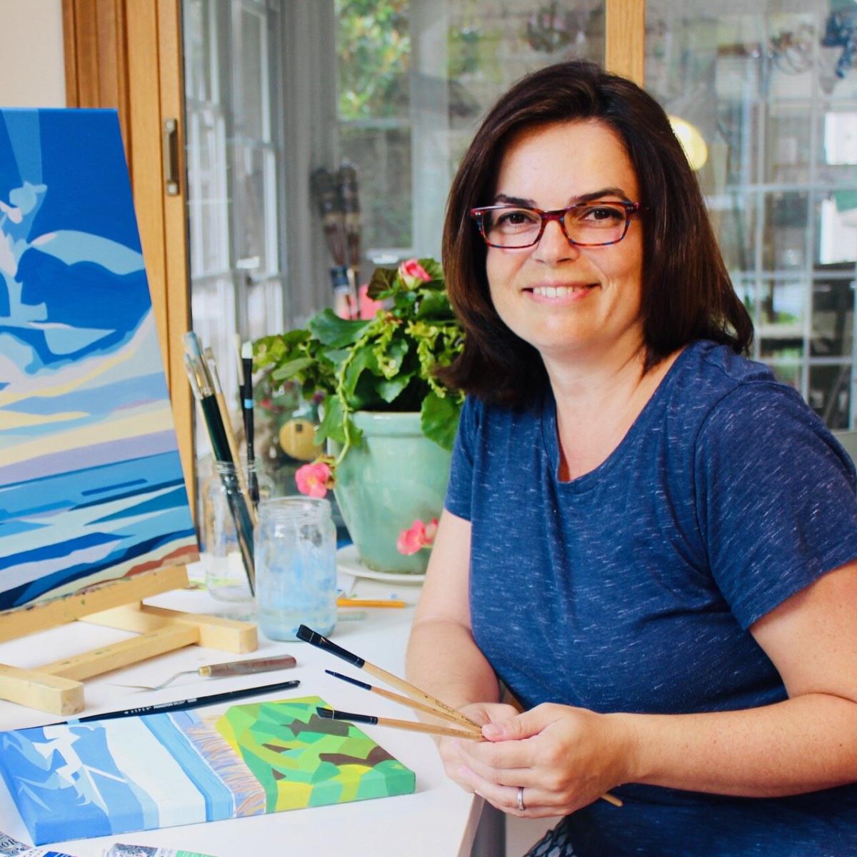 Woman sitting by easel and paints and brushes