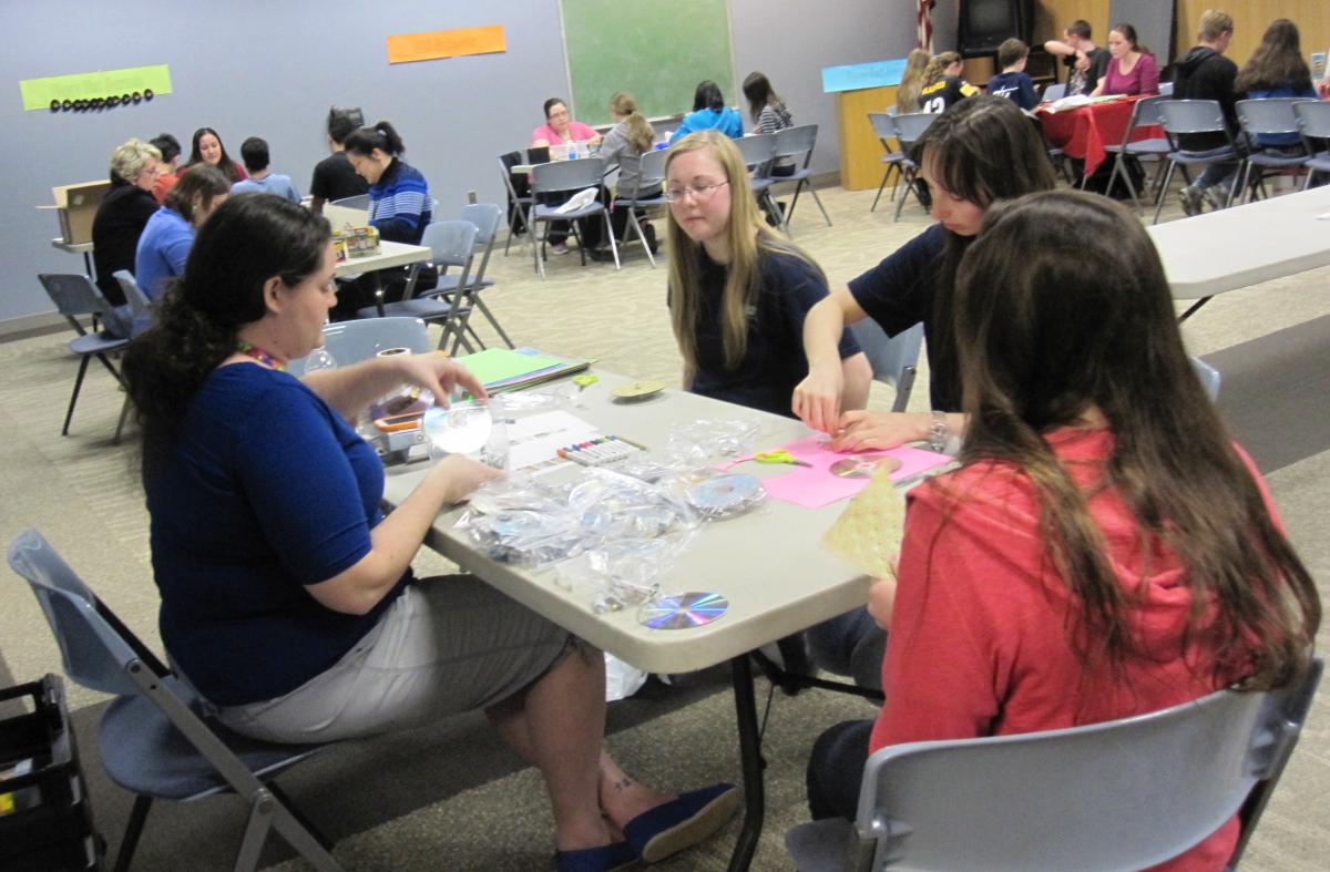 Teens doing a variety of activities at different stations for an event.