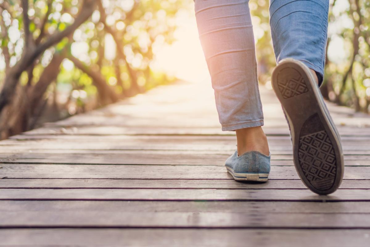 legs and feet of person walking on a boardwalk