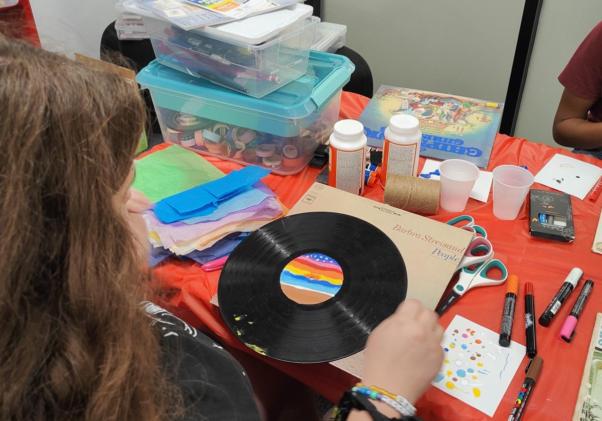teen girl decorating a vinyl record with paint pens and other art supplies