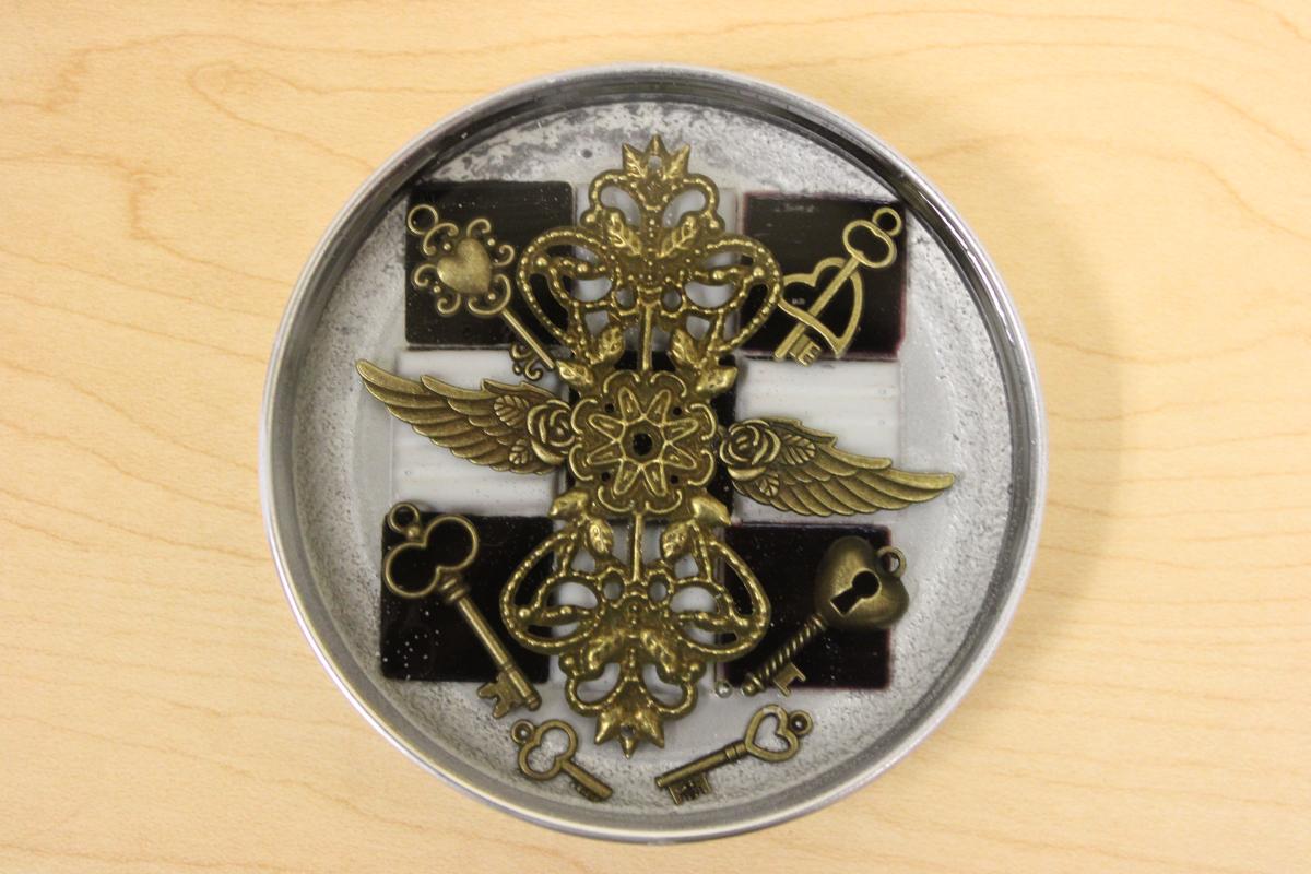 Metal mason jar lid filled with metal gears, and black and white tiles.