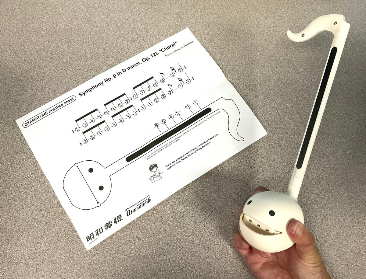 sheet music and hand holding white Otamatone