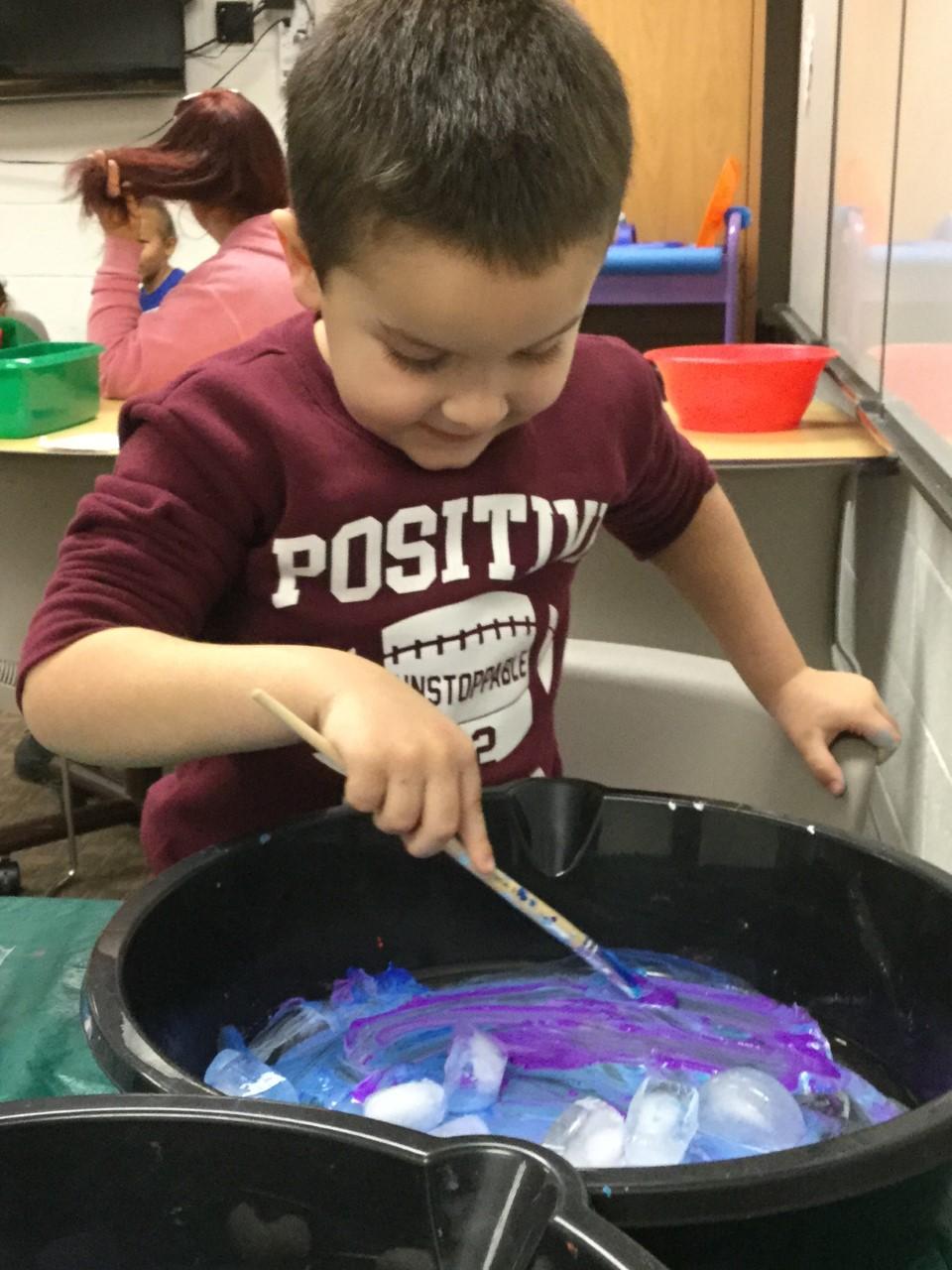 Child moving ice cubes to make a painting