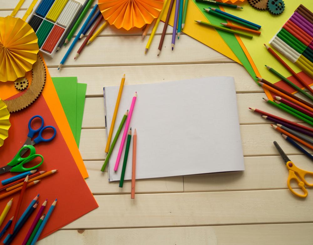 Colored paper, pencils, and scissors are on a table