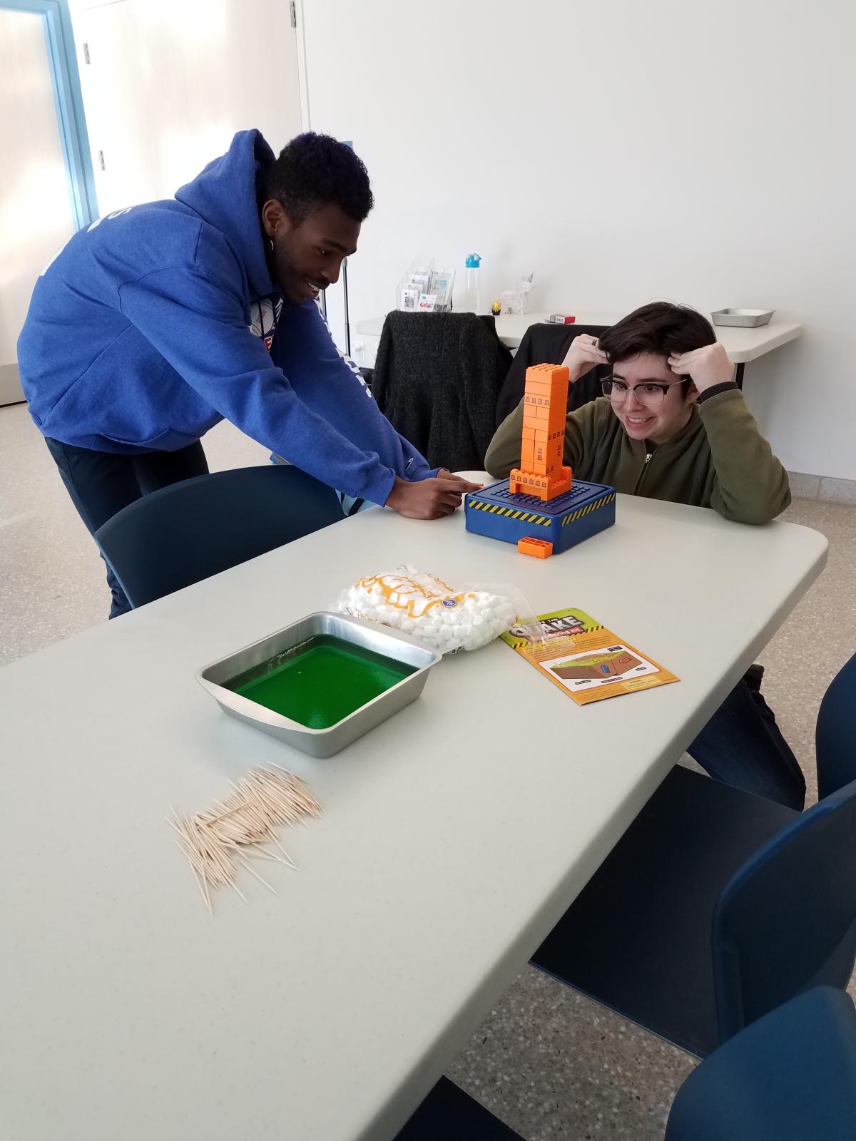 Two teens with earthquake simulator and tower of blocks