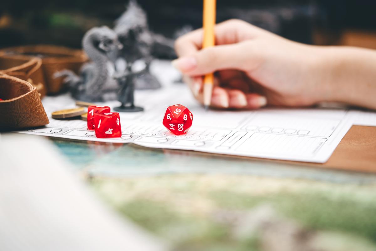 Hand writing with two red dice in foreground.