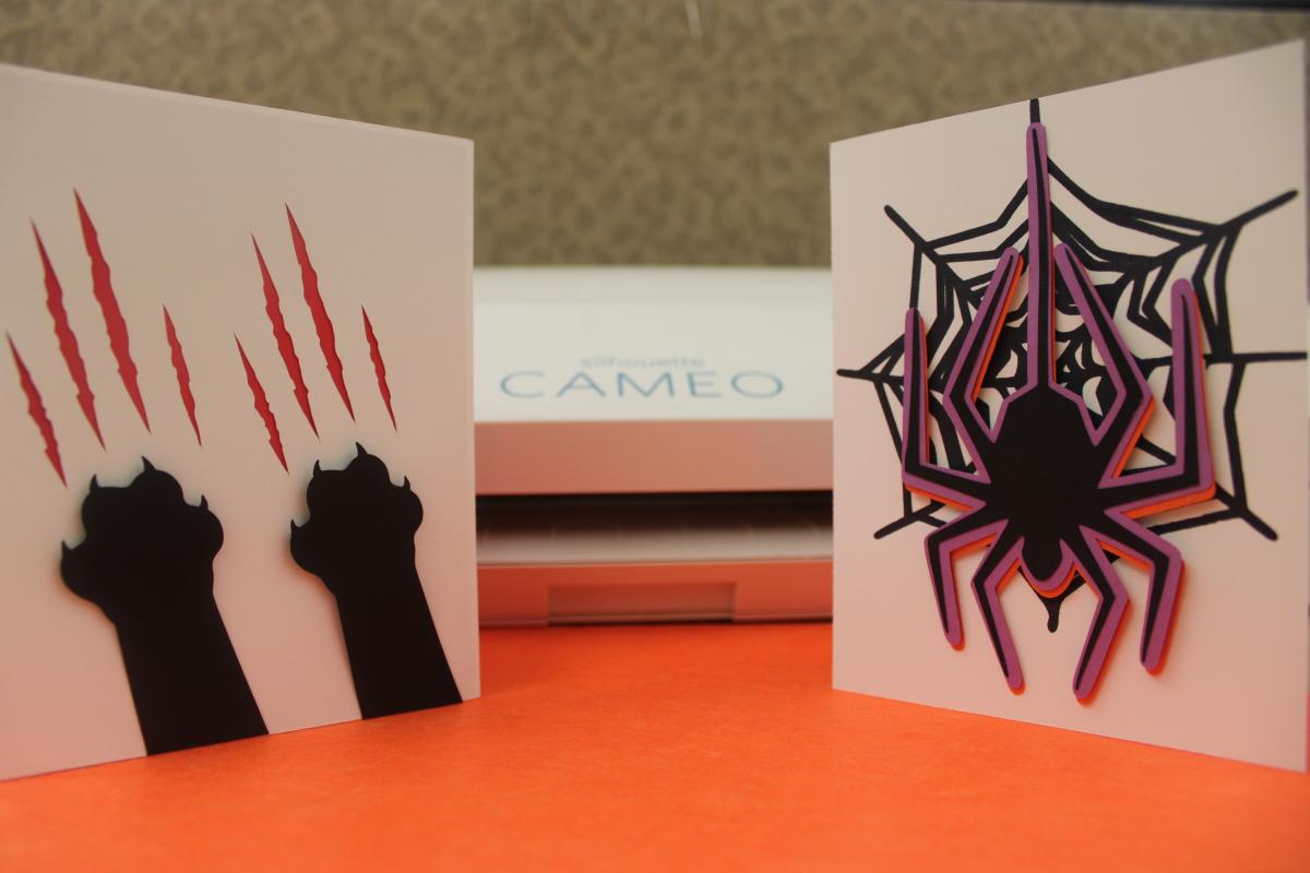 Cameo 3 machine in the background. Two Halloween themed greeting cards in front of the machine.