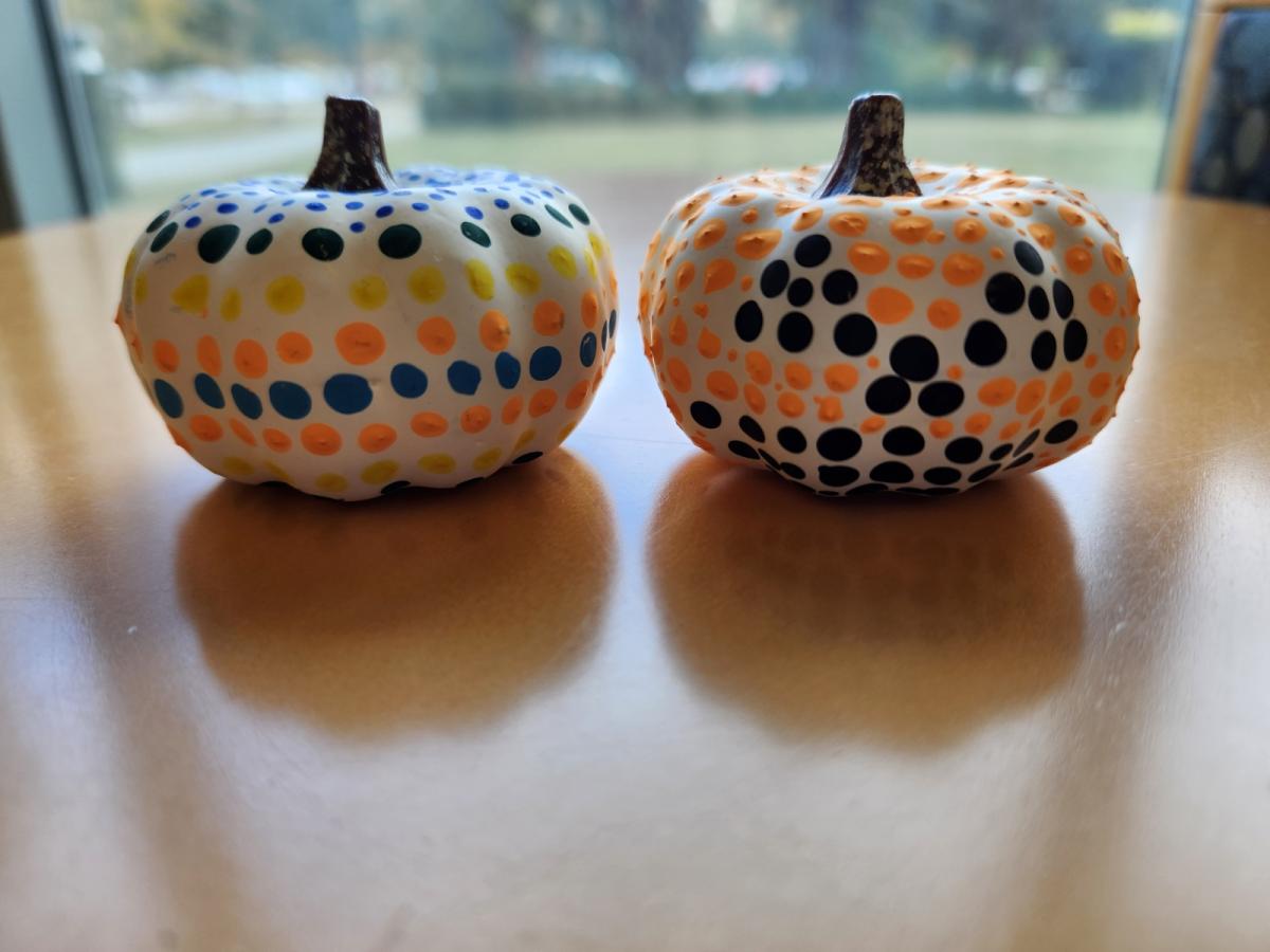 Two white pumpkins with painted dotted on in different patterns.