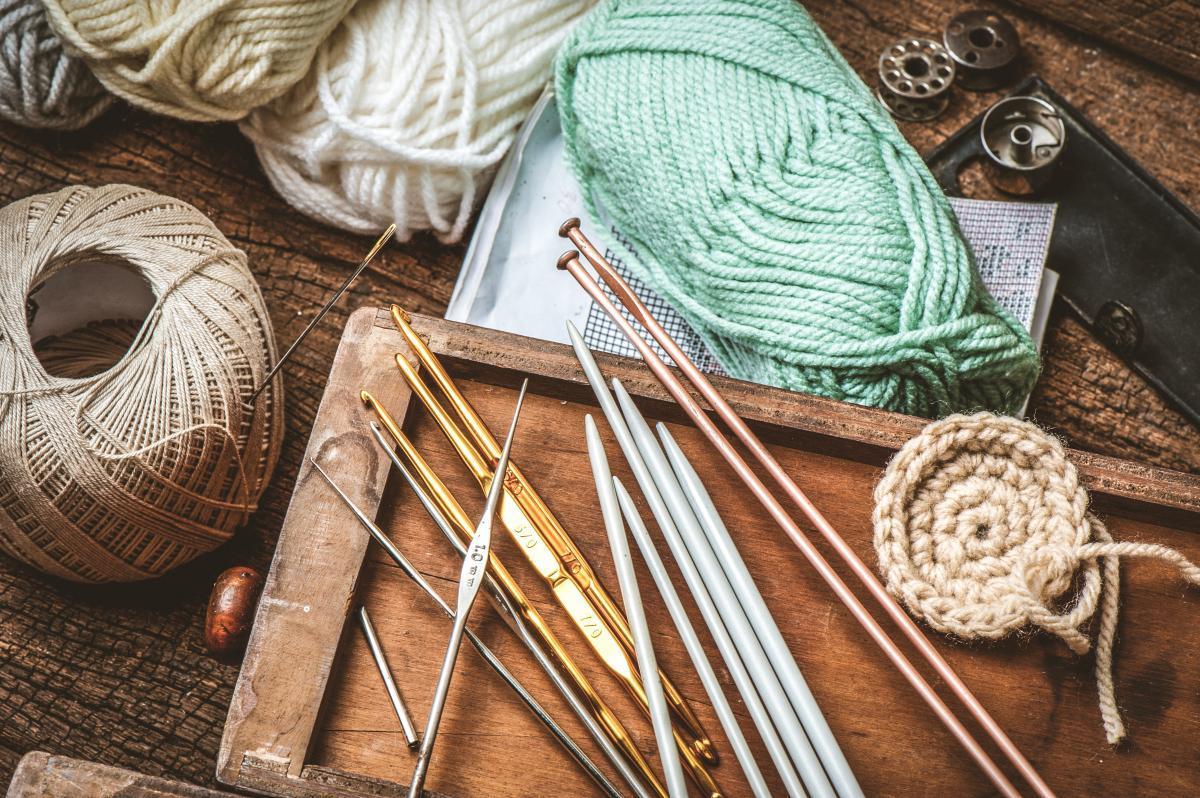 A table with crochet hooks, knitting needle, and yarn