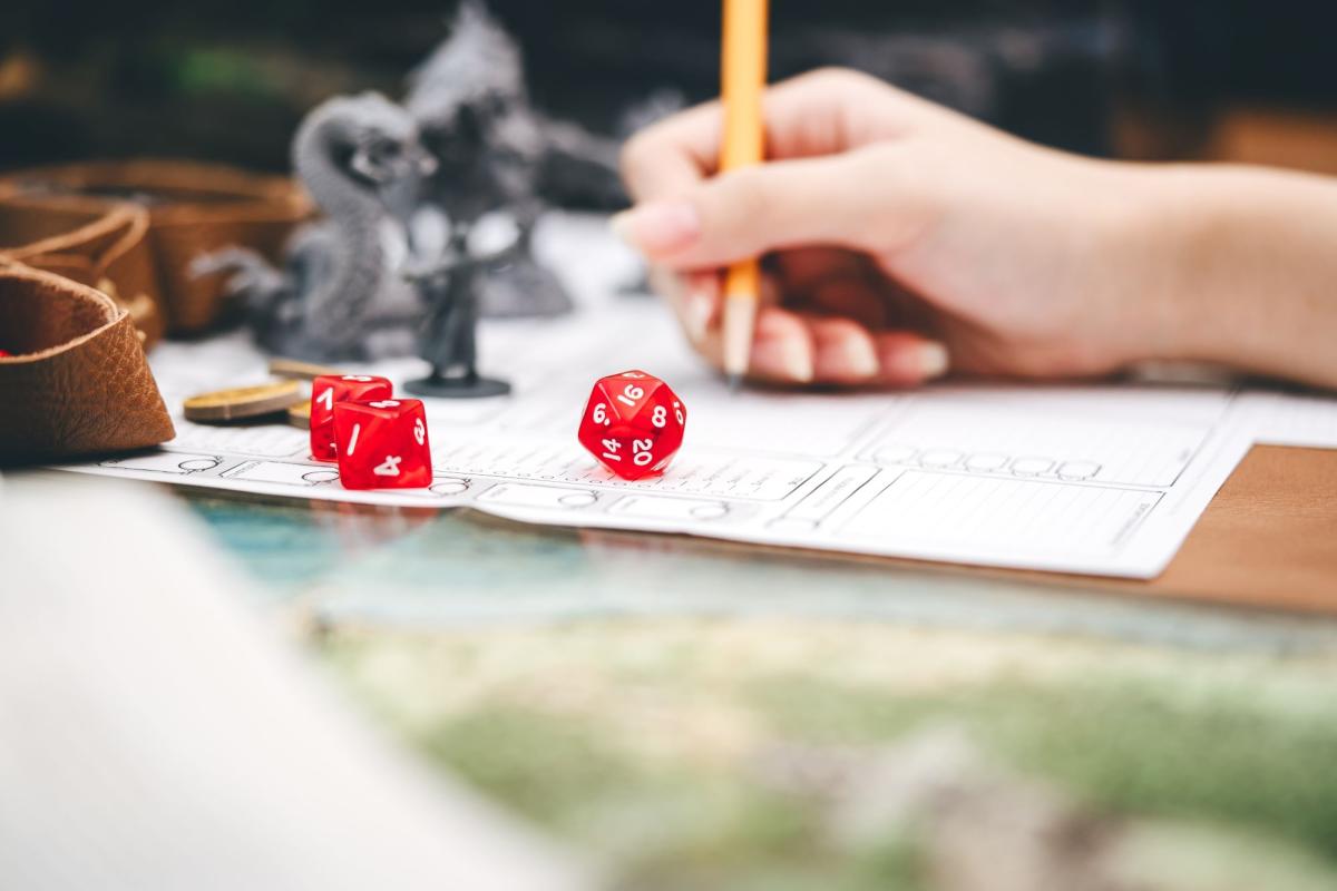 Hand writing with two red dice in foreground.